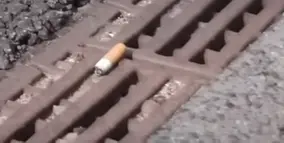 Picture shows cigarette butt on road, implying that someone smoked while driving/riding, causing others behind them to intake/inhale that smoke