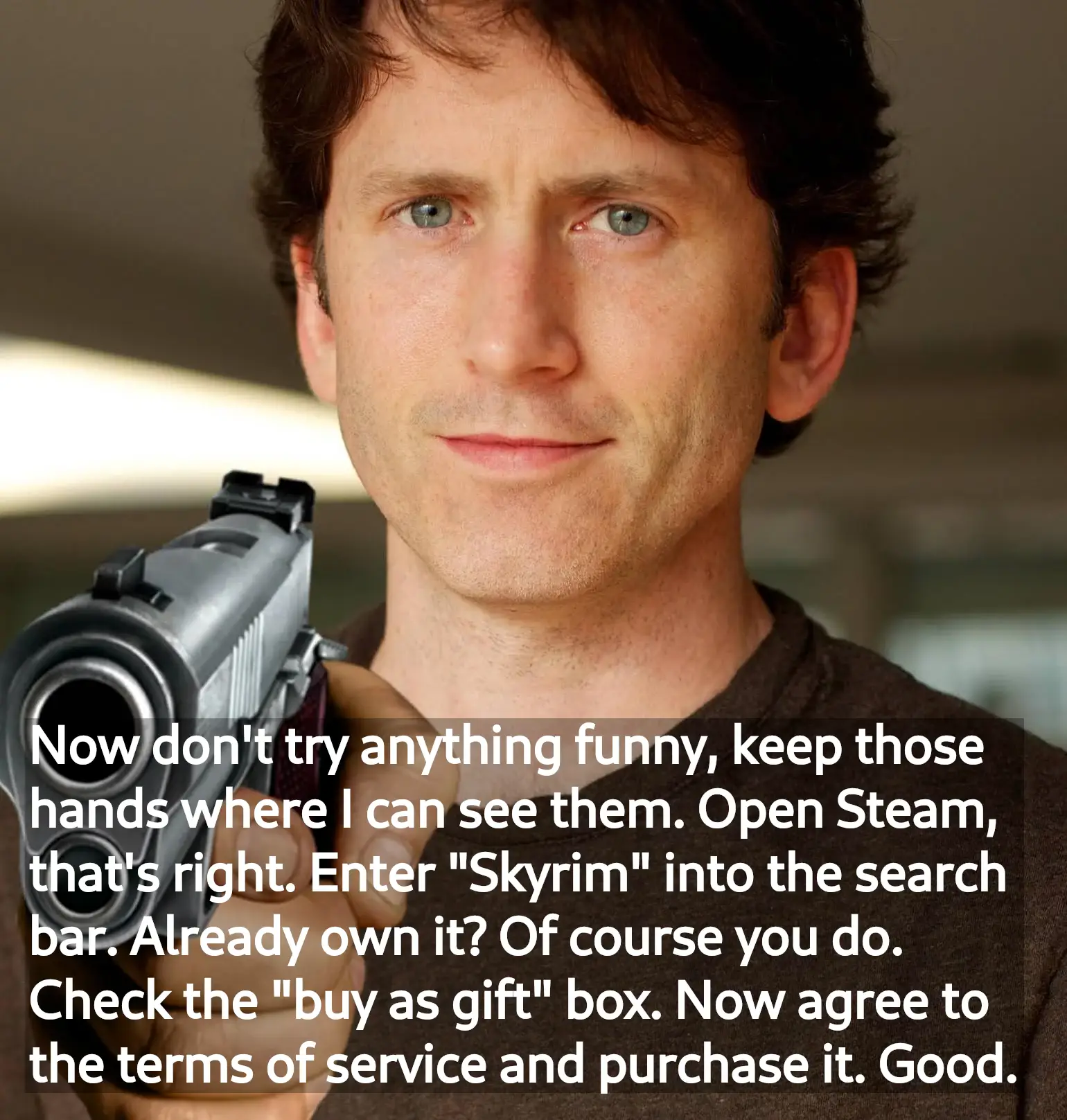 Todd Howard with a gun with the text: 'Now don't try anything funny, keep those hands where I can see them. Open Steam, that's right. Enter "Skyrim" into the search bar. Already own it? Of course you do. Check the "buy as gift" box. Now agree to the terms of service and purchase it. Good.'