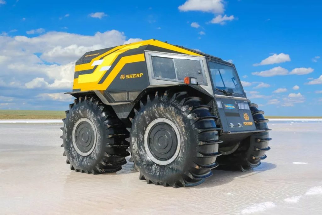 sherp all road vehicle depicted on the beach, the vehicle is quite small but its wheels are up to 5 feet in diameter