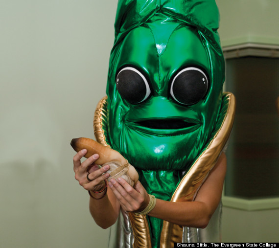 mascot has deep green skin, large eyes with huge pupils, flat wide mouth, and looks creepy while holding a real geoduck that looks as a trunk growing from a clam at best